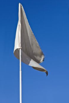 Portrait vertical of plain white silky flag fluttering in the breeze