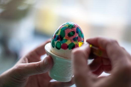 Hand painting of Easter eggs - close-up of hands and egg