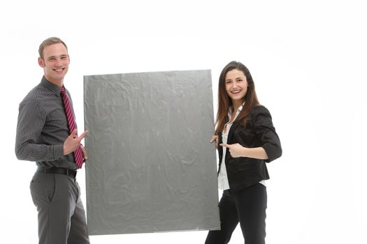 Successful smiling businessman and woman standing holding and pointing to a textured blank board ready for your copy