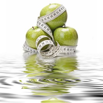 Measuring tape wrapped around a green apple as a symbol of diet.