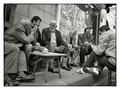 MATURE TURKISH MEN, ISTANBUL, TURKEY, APRIL 17, 2012: A group of Turkish men doing the world situation outside a tea house in urban Istanbul, Turkey.