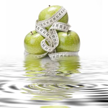 Measuring tape wrapped around a green apple as a symbol of diet.