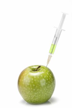 A syringe inserted  in an apple on a white background.