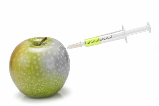 A syringe inserted  in an apple on a white background.