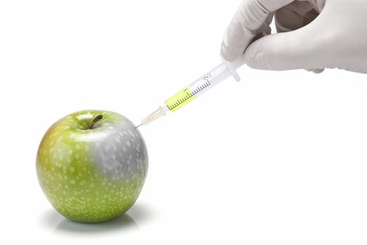 A gloved hand injecting an apple with a syringe on a white background.