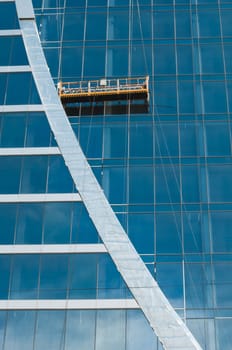 The glass wall of office building with windows and construction lift