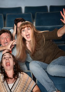 Scared Caucasian teen jumps out of her seat in theater