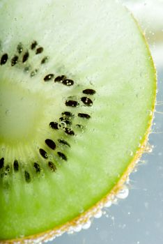 Slices of kiwi closeup backlit with seeds in water