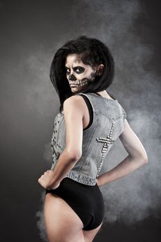 Young woman in day of the dead mask skull face art. Halloween face art with fog on black background