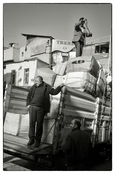 HIGH CARGO ON LORRY, ISTANBUL, TURKEY, APRIL 12, 2012: Workers loading a truck with goods in the low afternoon sun - Istanbul, Turkey.