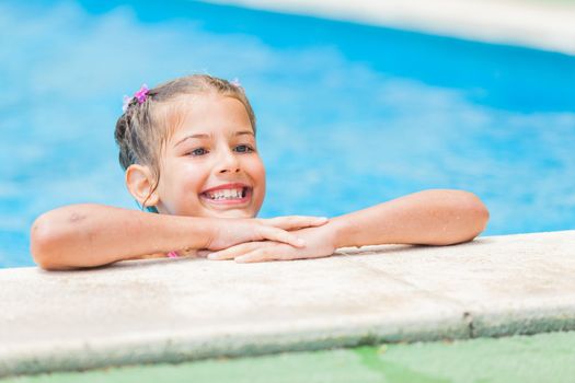 Pretty young smiling girl near a side of the pool