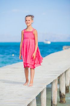 Cute teens girl walking on jetty with turquoise sea