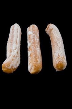 Picture of three frozen hot dogs on black