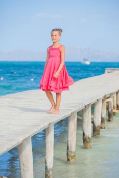 Cute teens girl walking on jetty with turquoise sea