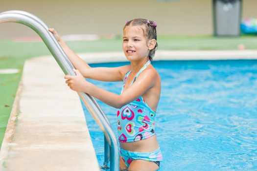 Pretty young girl stay at pool's edge