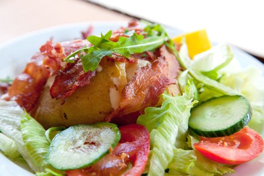 Jacket potato with sour cream and grated cheese on green salad