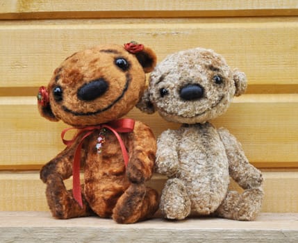 Teddy bears against a wooden wall. Handmade, the sewed plush toys