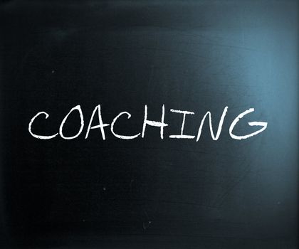 "Coaching" handwritten with white chalk on a blackboard.