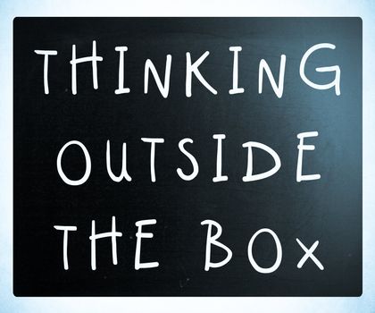 Thinking outside the box phrase, handwritten with white chalk on a blackboard