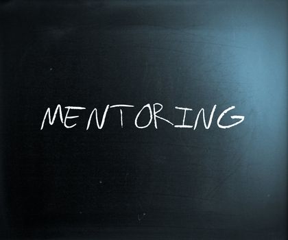 The word "Mentoring" handwritten with white chalk on a blackboard.