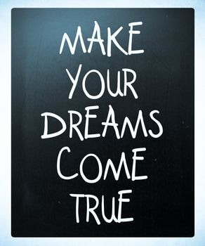 "Make your dreams come true" handwritten with white chalk on a blackboard