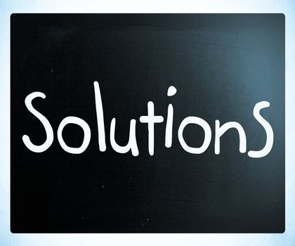 "Solutions" handwritten with white chalk on a blackboard