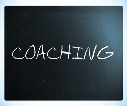"Coaching" handwritten with white chalk on a blackboard.