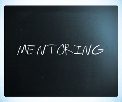 The word "Mentoring" handwritten with white chalk on a blackboard.