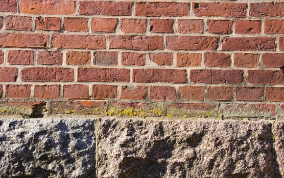 Background of ancient red brick wall and house foundations made of stone rock.