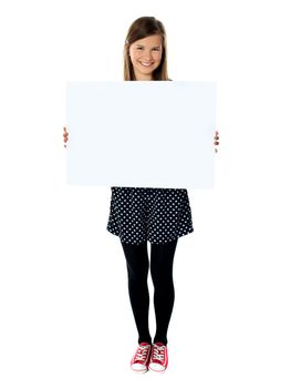 Attractive smiling cute girl holding blank poster against white background