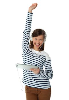 Trendy young girl enjoying music with raised arm, isoalted on white