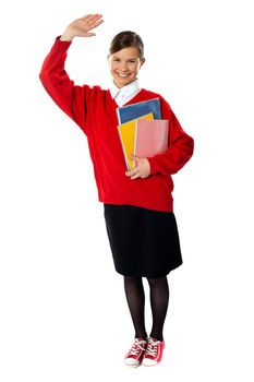 Full length view of student girl with giving hi5 and holding exercise books