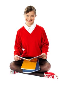 Pretty school girl sitting with crossed legs, books on her lap