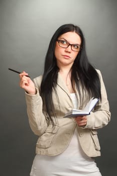 the serious girl, the brunette wearing spectacles looks up, on a gray background, looks in the chamber, a vertical shot