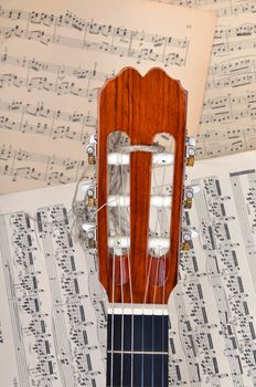 Top off a guitar resting against music notes.