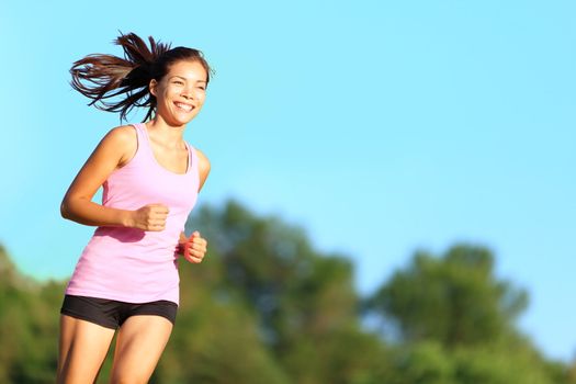 Happy woman running in city park. Asian girl runner jogging smiling aspirational outside on beautiful summer day. Mixed race Asian Chinese / Caucasian female fitness sport model training outdoors.