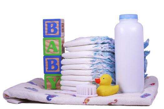 Items for a new baby, diapers, powder, receiving blanket, rubber duck, and brush isolated on white