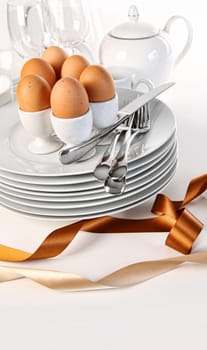 Brown eggs with plates for Easter breakfast on white