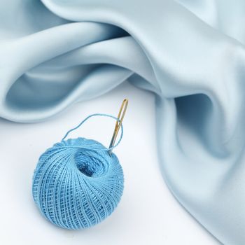 thread on blue silk isolated close up