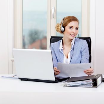smiling young female callcenter agent with headset in office