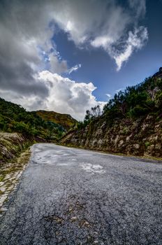Asphalt road in the mountains and blue sky with clouds.