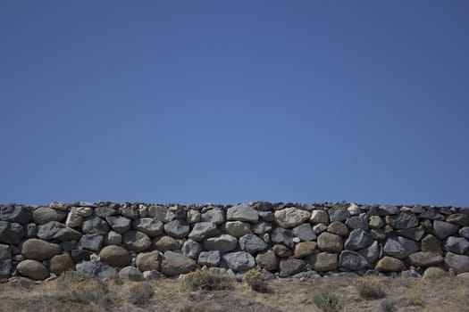 Rock boulder wall with a blue clear sky