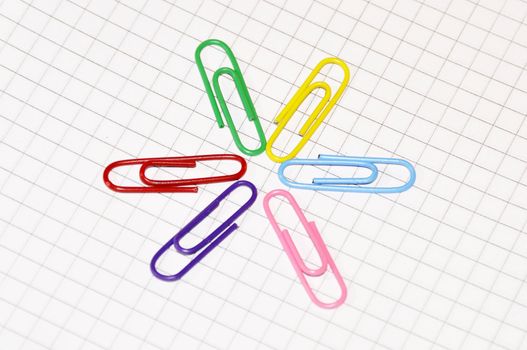 Multi-coloured paper clips laid out in a circle on a writing-book