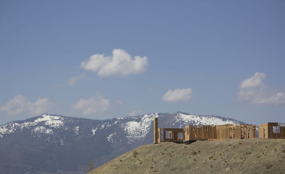 building a home on a ridge with the snowy mountains in the background