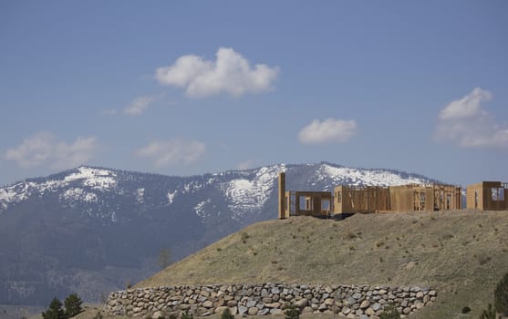 building a home on a ridge with the snowy mountains in the background