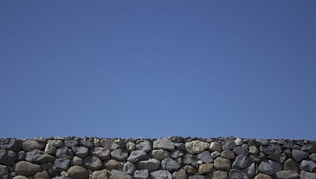 Rock boulder wall with a blue clear sky