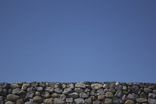 Rock boulder wall with a blue clear sky