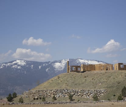 building a home on a ridge with the snowy mountains in the background