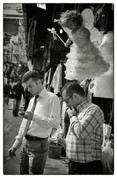 READING TEXT MESSAGE, ISTANBUL, TURKEY, APRIL 17, 2012: Two businessmen in the bazaar checking their mobile phones under a guardian angel - Istanbul, Turkey.