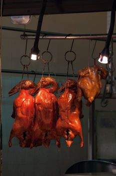 chinese bbq duck and chicken hang on a rack in a restaurant